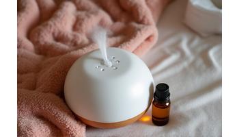 Aromatherapy diffuser with calming essential oils and a weighted blanket draped over a chair.