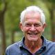 Active man in his late 60s, smiling outdoors.